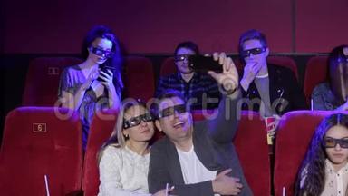 <strong>电影院</strong>里的<strong>情侣</strong>在看电影之前，戴着3D眼镜自拍。
